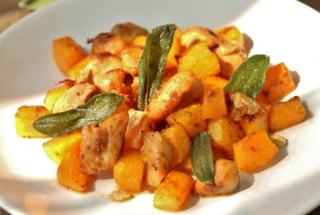 dish with pumpkin. fried chicken fillet and pumpkin cubes with sage (chips from sage). a dish on the table on a sunny day. autumn dish with pumpkin. sunlight. hard shadows