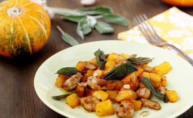 dish with pumpkin. fried chicken fillet and pumpkin cubes with sage (chips from sage). a dish on the table on a sunny day. autumn dish with pumpkin.