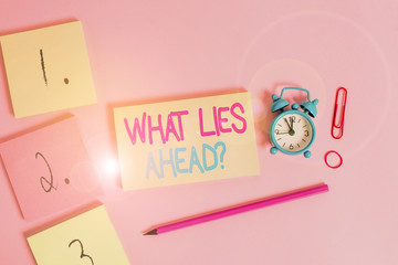 Writing note showing What Lies Ahead Question. Business concept for Asking for information about something on the way Blank notepads marker rubber band alarm clock clip colored background