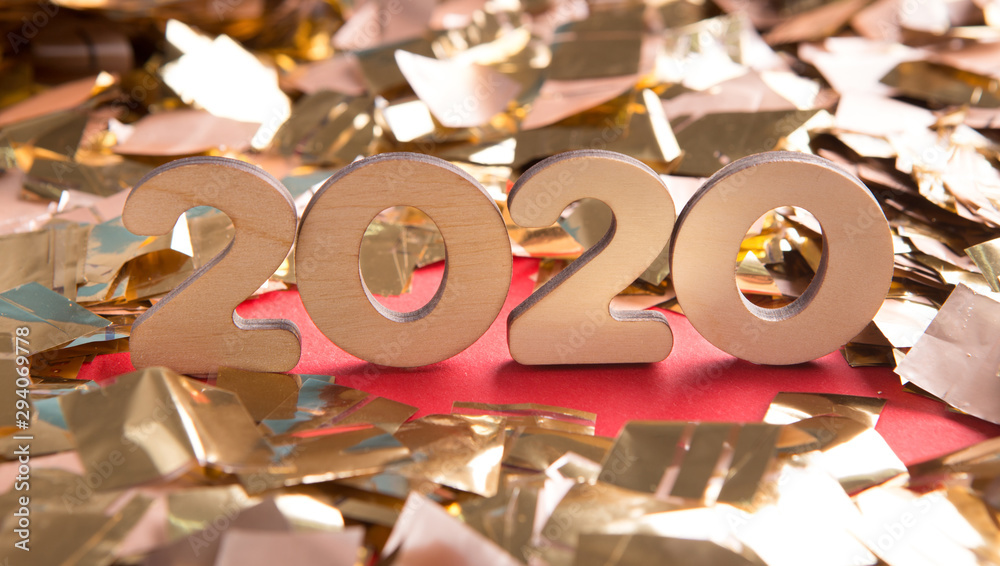 Poster close up of 2020 wooden text in confetti on red background