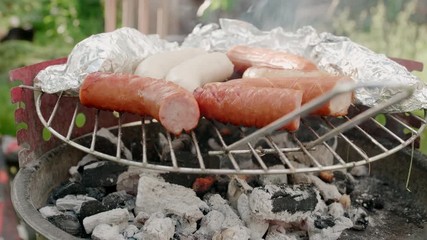 Close Up to Barbecue Grill with Meat Sausages and Food in Foil Grilling on Coal at Outdoors Picnic BBQ Party in Summer Weekend. 4K Static Background Shot