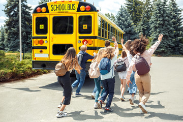 Being late. Classmates running to school bus back view waving to driver