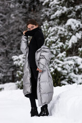 Lifestyle portrait of happy pretty young woman outdoors at snowing weather.