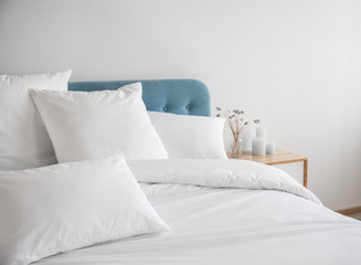 White pillows and duvet on the blue bed. White pillows, duvet and duvet case on a blue bed. White bed linen on a blue sofa. Bedroom with bed and bedding. Front view - obrazy, fototapety, plakaty