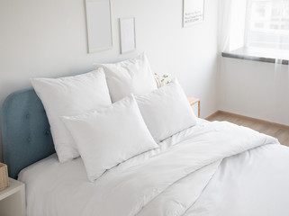 White pillows and duvet on the blue bed. White pillows, duvet and duvet case on a blue bed. White bed linen on a blue sofa. Bedroom with bed and bedding and poster frame mock up on the wall.Front view