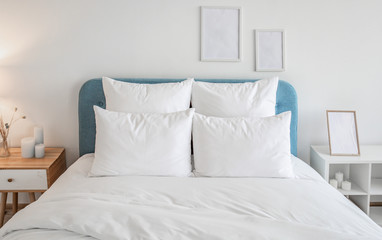 Fototapeta na wymiar White pillows and duvet on the blue bed. White pillows, duvet and duvet case on a blue bed. White bed linen on a blue sofa. Bedroom with bed and bedding and poster frame mock up on the wall.Front view