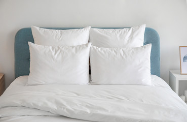 White pillows and duvet on the blue bed. White pillows, duvet and duvet case on a blue bed. White bed linen on a blue sofa. Bedroom with bed and bedding and poster frame mock up on the wall.Front view