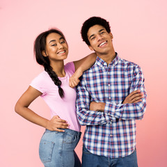 Teen couple posing over pink studio background