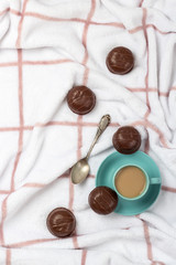 Flat lay of coffee cup and chocolate biscuits  arranged on fluffy blanket