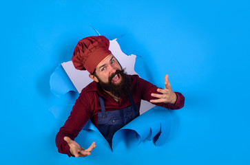 Bearded man in chef uniform looking through paper hole. Professional happy man chef. Cooking,...