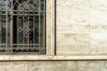 Detail of window with railings on a facade covered in stone