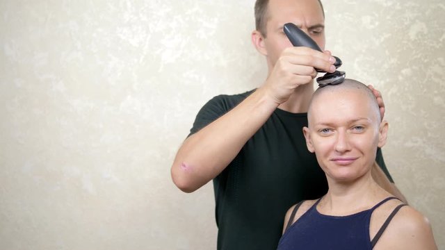 man shaves the head of a bald woman. copy space. adventures of strange people
