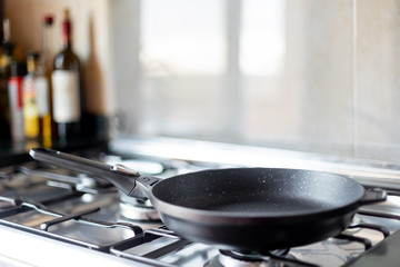 Empty clean frying pan on a stove in the modern kitchen - obrazy, fototapety, plakaty