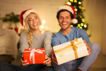 Fototapeta na wymiar Merry Christmas. Couple holding gift boxes, stretching to camera