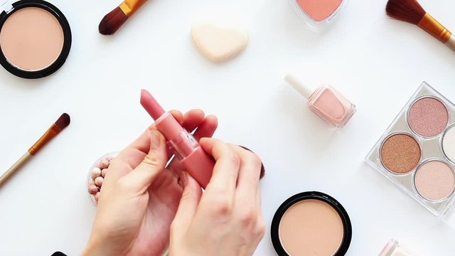 Female hand putting the cosmetic tools on makeup table. Top view