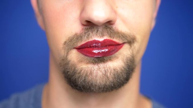 close-up. A bearded man with painted lips licks them sexually.