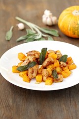 dish with pumpkin. fried chicken fillet and pumpkin cubes with sage (chips from sage). a dish on the table on a sunny day. autumn dish with pumpkin.