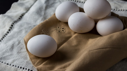 Fresh eggs in a brown cloth napkin with black background. Space to copy 