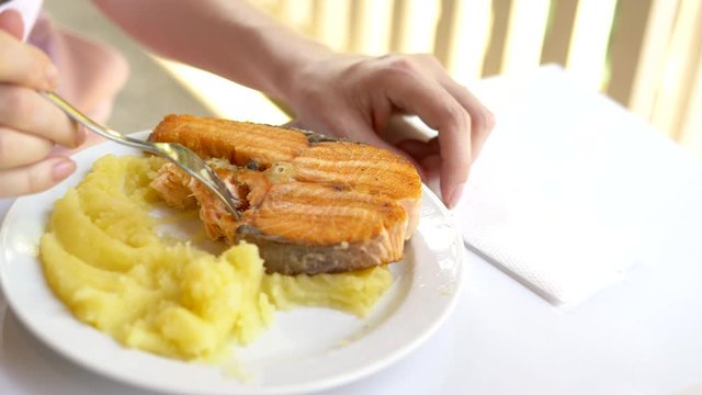 close-up. someone eating red fish steak with mashed potatoes with a fork
