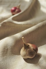 Two garlic bulbs on a linen tablecloth