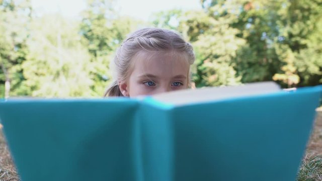 Concentrated schoolgirl reading fairytale book studying subject, knowledge