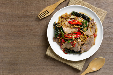 top view of stir fried sizzle pork in a ceramic dish on wooden table. asian homemade style food concept.