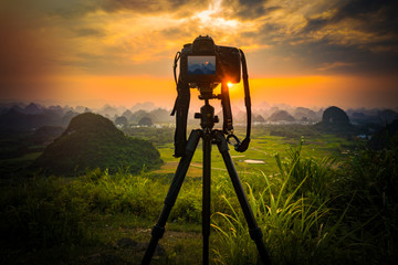 Camera on tripod and photography view camera with blurred focus landscape of sunset sunrise sun...