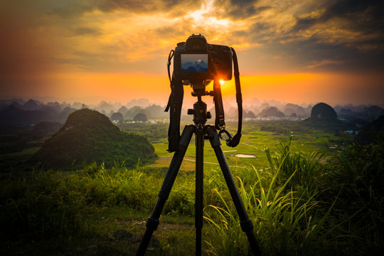 Camera on tripod and photography view camera with blurred focus landscape of sunset sunrise sun light sky cloud