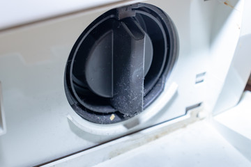 Black cover of washing machine drain pump filter close up