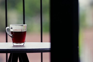 Hot black coffee in clear glass on the table at balcony. Morning cup of hot coffee on the table. soft focus.