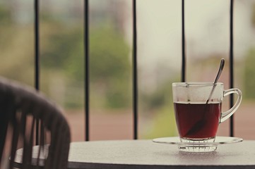 Hot black coffee in clear glass on the table at balcony. Morning cup of hot coffee on the table. soft focus.