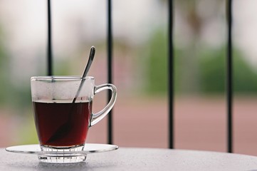 Hot black coffee in clear glass on the table at balcony. Morning cup of hot coffee on the table. soft focus.