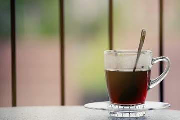 Hot black coffee in clear glass on the table at balcony. Morning cup of hot coffee on the table. soft focus.