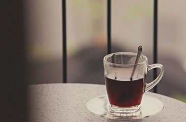 Hot black coffee in clear glass on the table at balcony. Morning cup of hot coffee on the table. soft focus.
