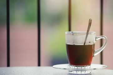Hot black coffee in clear glass on the table at balcony. Morning cup of hot coffee on the table. soft focus.