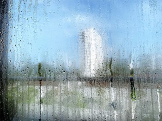 Transparent Glass with drops of water and can see through the glass outside of the business building area but it is not clear. Vapored or steam on mirror when raining.
