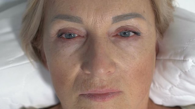 Shocked woman lying in bed and looking around, patient recovering from coma