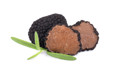 Black truffles isolated on a white background. Fresh sliced truffle with rosemary branch. Delicacy exclusive truffle mushroom. Piquant and fragrant French delicacy. Clipping path.