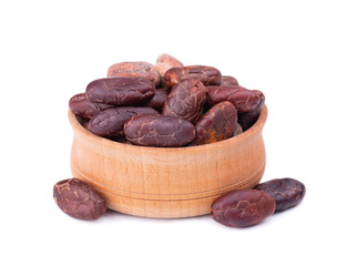 Peeled cocoa beans in the wooden bowl, isolated on white background. Roasted and aromatic cocoa beans, natural chocolate.