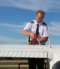 Flight instructor pilot filling the airplane with jet fuel with hair blowing in the wind © Diane