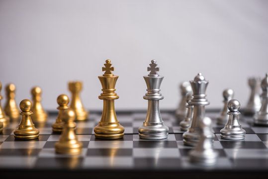 gold against silver chess pieces on chess board