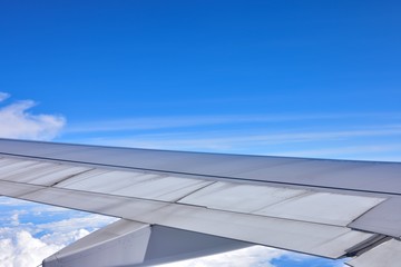 Fototapeta premium Close-up the airplane wing flying in the sky. Blue sky and cloudy background.