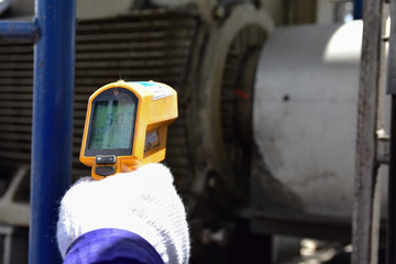 Worker are measuring the temperature of motor with infrared thermometer (Temp gun).