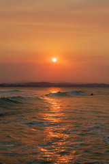 Surfer goes out to enjoy the waves during sunset at Snapper Rocks, Queensland, Australia.