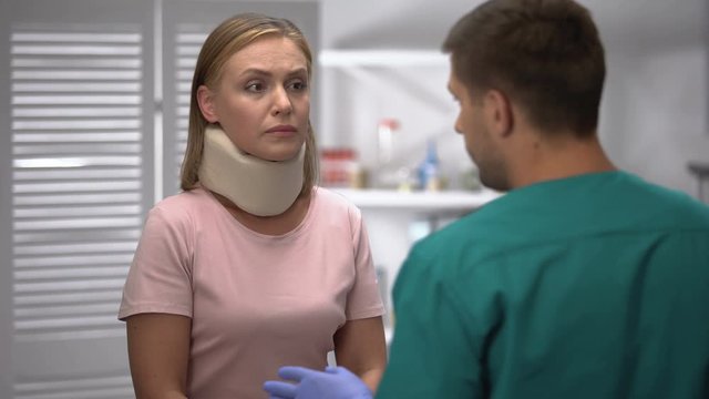 Orthopedist checking female foam cervical collar position, informing diagnosis