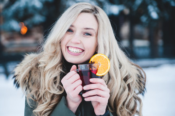 Beautiful smiling woman with mulled wine outdoor.
