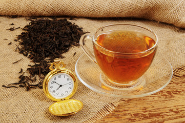 Tea cup with pocket watch on rustic background