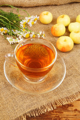 Camomile tea and apples on burlap sack background