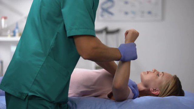 Traumatologist exercising female patient hand after trauma rehabilitation period