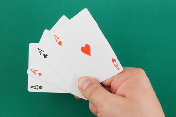Aces in hand on green table background